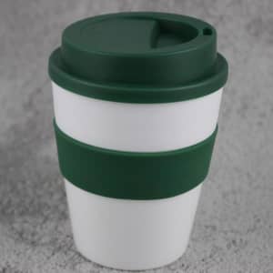 A plastic coffee cup in white with a green silicone sleeve and lid, featuring a logo on the side.