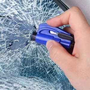 A blue car escape tool with a seatbelt cutter is being used on a shattered car window.