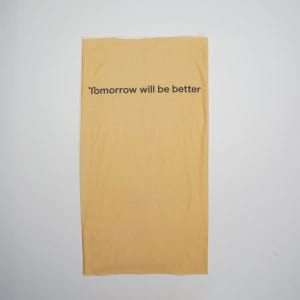 A yellow multifunctional neck gaiter with a motivational phrase printed on it. It features a logo.