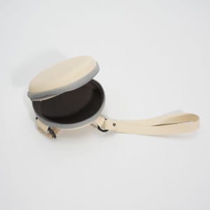 A cream-coloured folding eyeglasses case with a zippered opening and a carrying strap. The interior is dark.