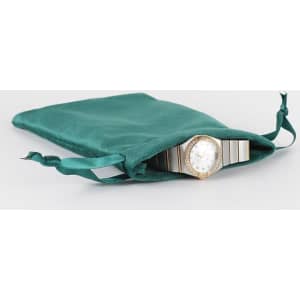 A teal velvet gift bag with a watch partially visible inside, featuring a decorative drawstring closure.