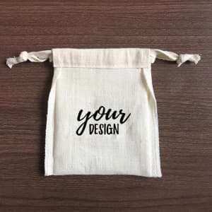 A natural cotton drawstring bag featuring a customizable design and tied closure.