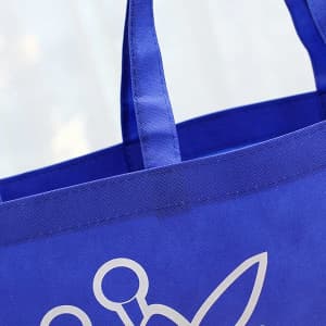 A blue non-woven grocery bag featuring sturdy handles and a logo design.