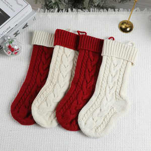 Four large cable knitted Christmas stockings in red and cream, featuring a textured design and ribbed tops.