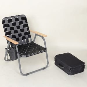 A folding webbed camping chair in black and grey, with wooden armrests, next to a black carrying bag.