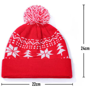 A red Christmas beanie featuring a white design with trees and snowflakes, topped with a pom-pom. It includes a logo.