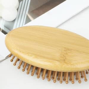 A bamboo massage comb with rounded edges and wooden bristles on a flat surface, surrounded by neutral tones.