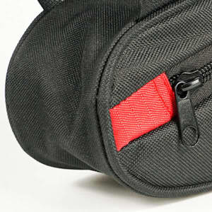 A black bike triangle bag features a red zipper tab and textured fabric, with a logo visible on the side.