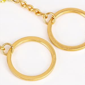 A custom metal keychain featuring two circular gold rings connected by a chain.