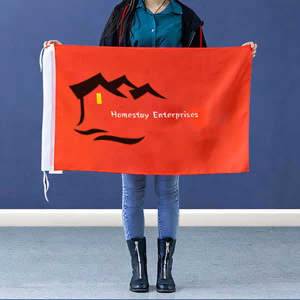 A large red hand waving flag held by a person, featuring a logo and design with a mountain and house.