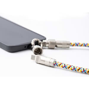 A multi-functional charging cable with a colourful braided design, featuring metal connectors, attached to a smartphone.