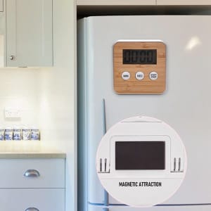 A multi-function electronic kitchen timer with a bamboo finish, displaying a digital countdown, mounted on a white fridge.
