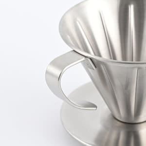 A stainless steel coffee dripper with a handle and a matching base, featuring a shiny, metallic finish.