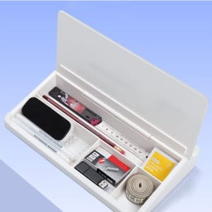 A white desktop organiser containing a ruler, markers, a USB, tape, and an eraser, with a hinged lid.
