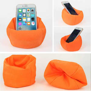 An orange bean bag phone holder displays a smartphone, featuring a soft, flexible design. It includes a logo.