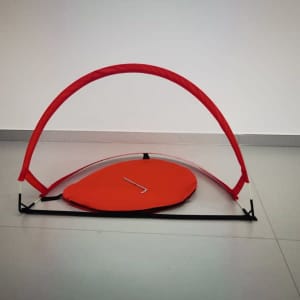 A pop-up football goal in vibrant red, featuring a curved frame and flat base, showcasing an organised design.