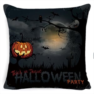 A Halloween-themed pillow featuring a pumpkin, bats, and a spooky tree against a dark backdrop. Has logo branding.
