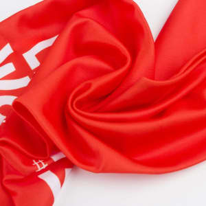A red custom sports fan scarf with a smooth texture and a logo or branding present.