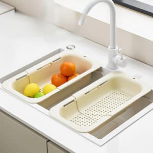 An extendable kitchen sink colander in cream colour, featuring two sections for rinsing fruits.