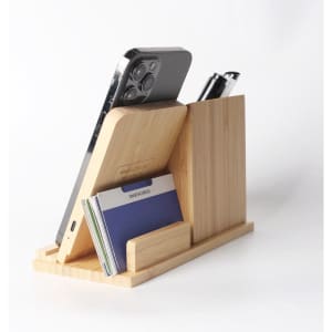A bamboo pen holder with a wireless charger, featuring compartments for a phone, cards, and pens.