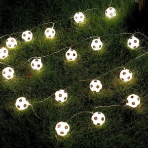 A string of 1.5m football-shaped lights on a grassy surface, glowing softly in white.