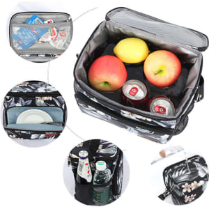 A large insulated lunch bag in black with floral pattern, containing apples, drink cans, and plates inside.
