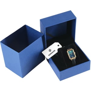 A rectangular quartz watch with a teal face and black strap, displayed in a blue gift box.