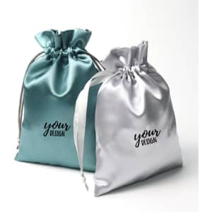 A set of two satin drawstring bags in teal and silver, featuring a logo or branding on the front.