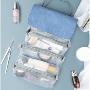 A blue and grey detachable roll-up makeup bag with multiple transparent compartments and skincare products.