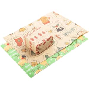 Colourful personalised gift wrapping paper featuring Christmas-themed designs, with a small wrapped gift on top.