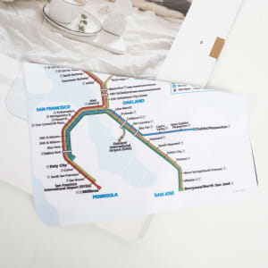 A custom eyeglasses cleaning cloth featuring a colourful transit map design. The cloth has a logo in one corner.