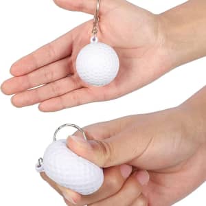 A golf ball stress reliever key chain in white, held in a hand, featuring a textured surface and a keyring attachment.