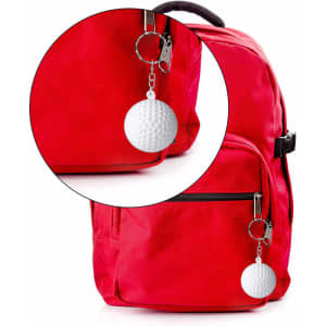 A white golf ball stress reliever key chain attached to a red backpack, featuring a metal clip and a textured surface.