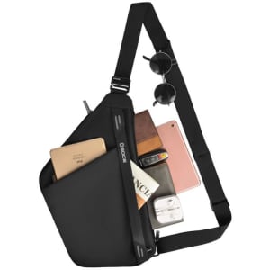 A black sling bag with sunglasses, a phone, a wallet, and a notebook visible in its pockets. Features a logo.
