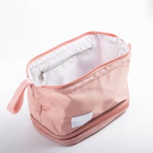 A pink double layer cosmetic bag featuring a brush compartment and a zippered pocket inside.