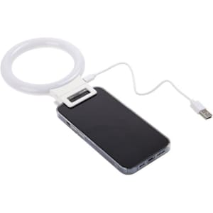 A white selfie ring light with a clip, connected to a smartphone via a USB cable.