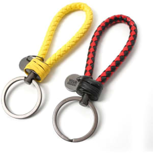 A unisex braided leather rope keychain in yellow and red, featuring a metal keyring and a logo tag.