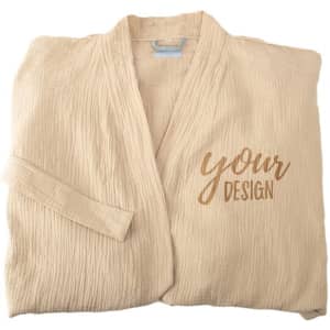 A beige long cotton bathrobe features a soft texture and an embroidered design area, folded neatly.