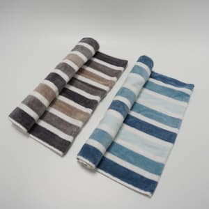 A rolled striped towel set featuring shades of beige, grey, and blue, with a soft fabric texture. Each towel has a logo.