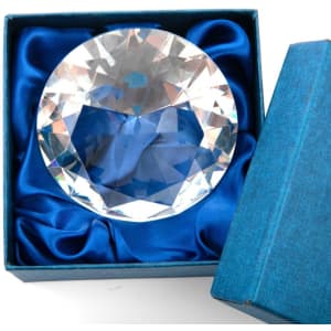 A diamond-shaped paperweight with a clear, faceted design inside a blue presentation box.