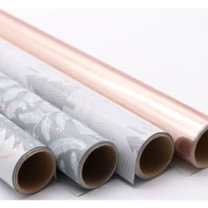 Four rolls of customised gift wrapping paper in grey with patterns and shiny rose gold, featuring a branding logo.