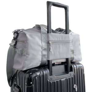 A grey large capacity duffel bag sits atop a black suitcase, featuring a handle and a zippered pocket.