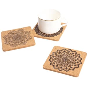 A set of square cork coasters displaying intricate mandala designs, accompanied by a cup.
