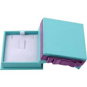 A turquoise gift box with a purple ribbon, featuring a white inner compartment for jewelry storage.