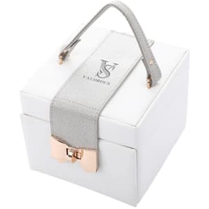 A white square jewelry box with a grey handle and a metallic rose gold bow detail. It features a branding logo.