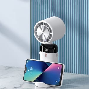 A white handheld fan with a phone holder, featuring a digital clock, set against a blue backdrop.