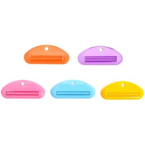 A set of five toothpaste tube squeezer dispensers in orange, pink, purple, blue, and yellow. Each has a rounded shape.