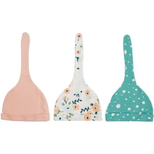A collection of three newborn baby knotted hats in peach, floral print, and turquoise with polka dots, featuring a logo.