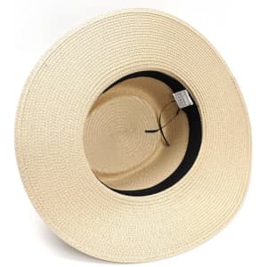 A beige wide brim Panama straw hat with a black inner lining and a logo tag.