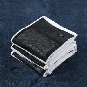 A golf towel folded neatly in white and black, featuring a zippered pocket and a logo.